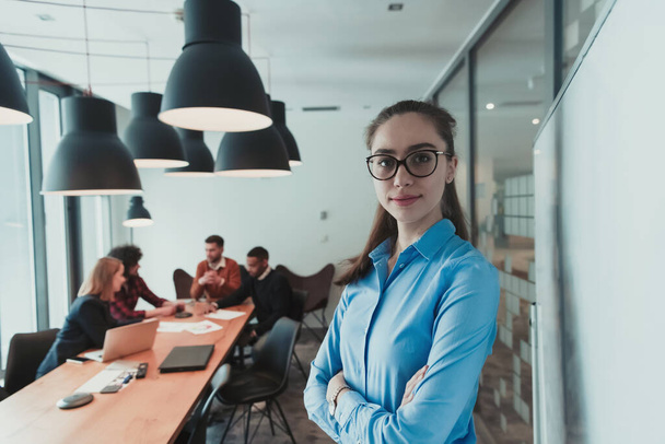 Portrait of happy businesswoman owner in modern office. Businesswoman smiling and looking at camera. Busy diverse team working in background. Leadership concept. Head shot. - 写真・画像