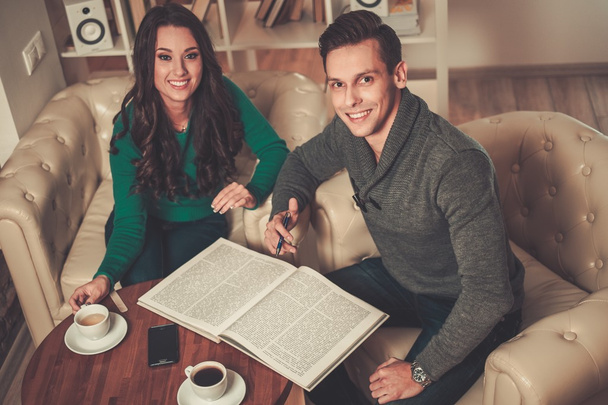Fiatal férfi és nő könyv és kávé tábla mögött  - Fotó, kép