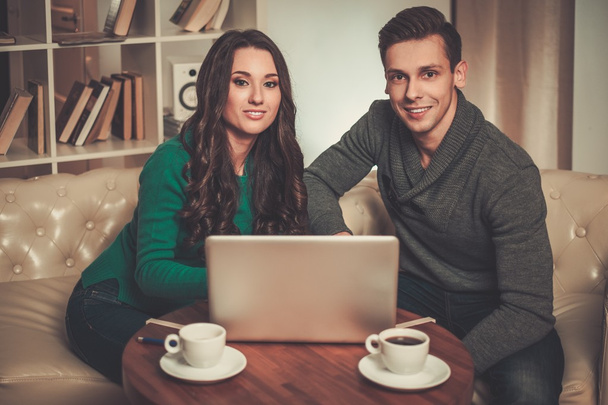 Young couple with laptop and coffee behind table - Photo, Image