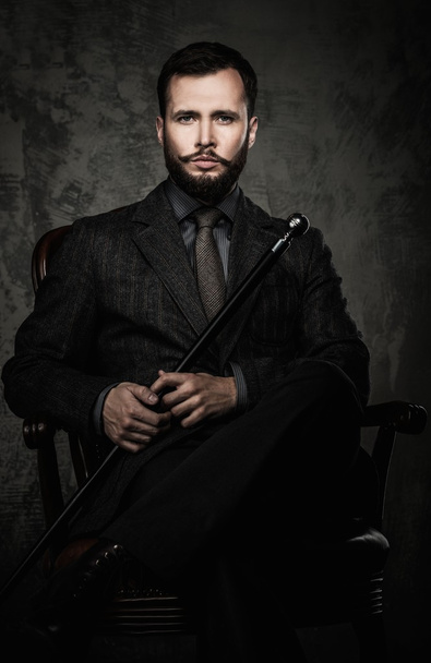 Hombre guapo bien vestido con bastón sentado en silla de cuero
  - Foto, Imagen
