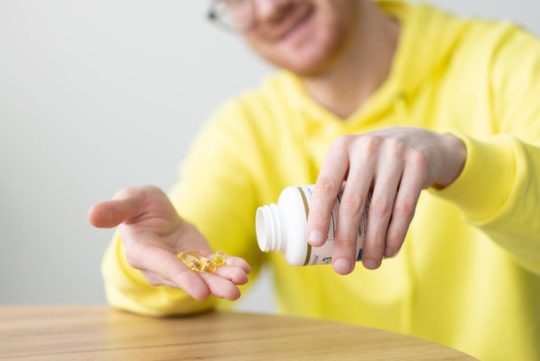 Smiling man takes vitamins out of the bottle. Closeup. Healthcare and medicine. - Photo, Image