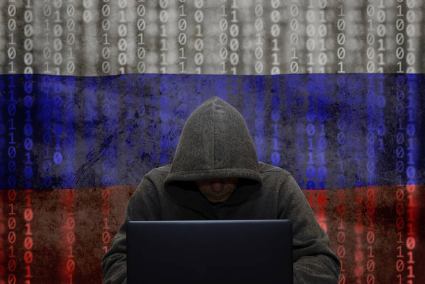 A trollgyár. Egy hacker ül egy laptopnál és az orosz zászló hátterében, megtámadja és feltöri a vállalati szervereket egy vírussal. Koncepció: DDOS támadás, hamis hírek. - Fotó, kép