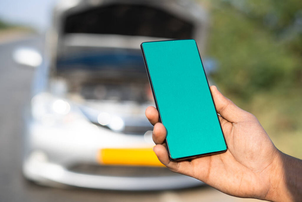 Lähikuva laukaus kädet osoittavat vihreä näyttö matkapuhelin edessä rikki auton moottoritiellä käsite online-varaus mobiili korjauspalvelu, - Valokuva, kuva