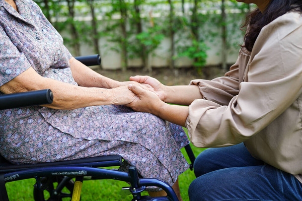 Gondozó segít ázsiai idős nő fogyatékosság beteg ül kerekesszékben a parkban, orvosi koncepció. - Fotó, kép