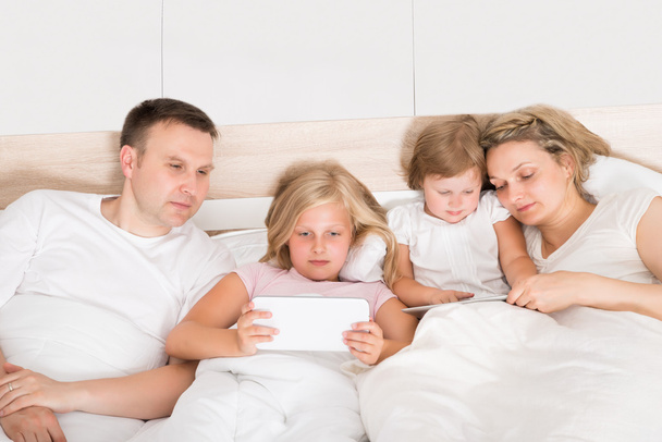 Jeune famille utilisant des ordinateurs portables au lit
 - Photo, image