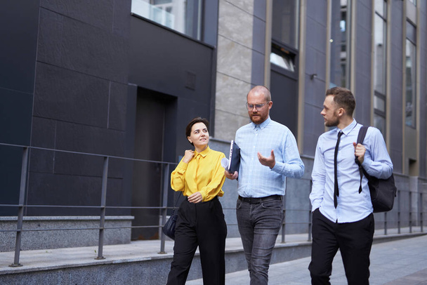 Groep gelukkige zakenmensen die voor het kantoor lopen - Foto, afbeelding