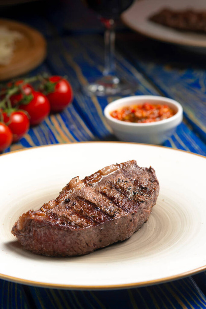 Roasted steak ,cherry tomatoes, salt and pepper on blue  wooden table. - Фото, изображение