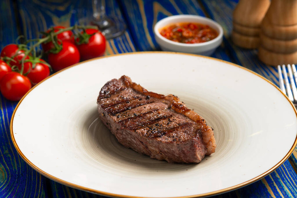 Roasted steak ,cherry tomatoes, salt and pepper on blue  wooden table. - Fotoğraf, Görsel