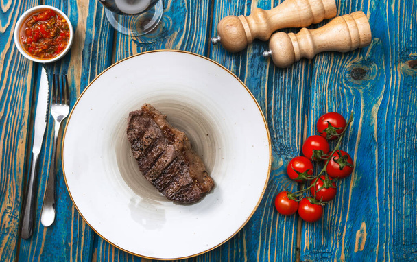 steak in white plate and a glass of wine on the table, top view - Фото, зображення
