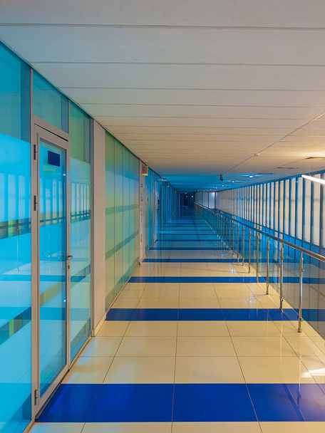An empty long corridor with blue-and-white glass walls and doors. Office space. - Photo, Image