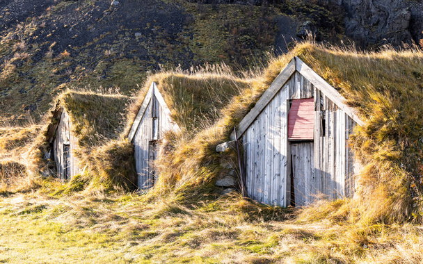 У південній Ісландії на схилі пагорбів височіють фермерські будівлі та багатоквартирні будинки. Ці трав'яні будинки є традиційними і збудованими для ізоляції від холодної суворої зими.. - Фото, зображення
