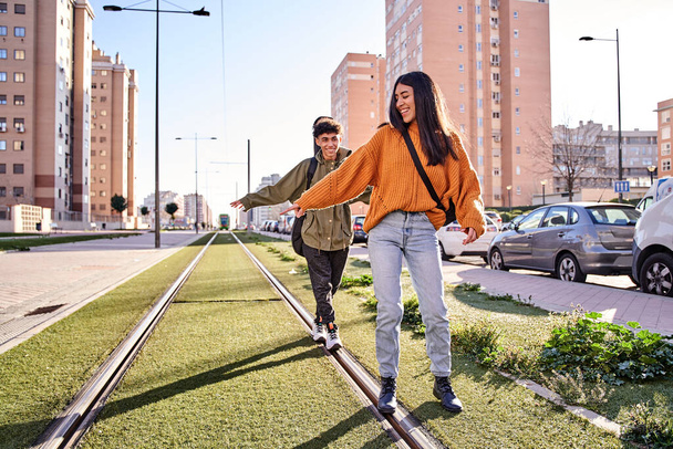 couple balancing on the train or tram tracks while laughing. youth and leisure concept - Photo, Image