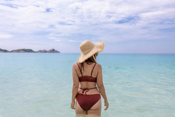 back view of woman wearing a straw hat and orange bikini relax on the beach with beautiful blue sky.at Similan island Phuket Thailand , summer vacation concept - Foto, Bild