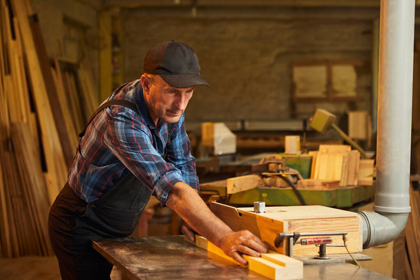 Schreinermeister in Uniform arbeitet an einer Holzbearbeitungsmaschine in der Schreinerei - Foto, Bild