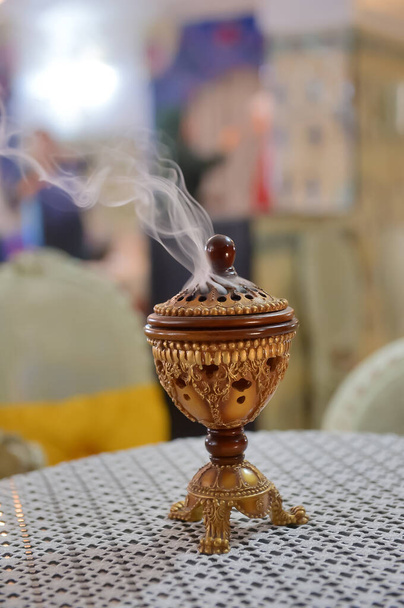 Pequeño metal decorativo árabe Bakhoor incensario incensario con humo y fondo borroso - Foto, Imagen