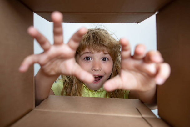 Amazed surprised shocked little boy peeking inside gift box, unpacking present with funny astonished expression, impatient child unboxing surprise. Children expression surprised face. - Foto, imagen