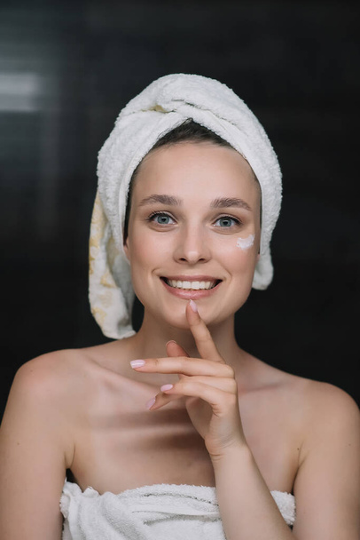 Happy woman in the bathroom looking at camera and touches her skin - Фото, зображення