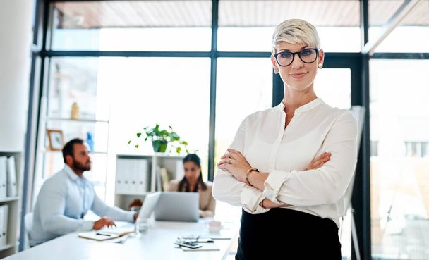 I can be a mom and go-getter all in one. Portrait of a pregnant businesswoman standing in an office with her colleagues in the background. - Foto, Bild