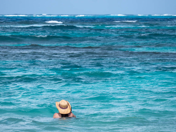 Frau mit Panama-Hut in den Wellen der Karibik von hinten - Foto, Bild