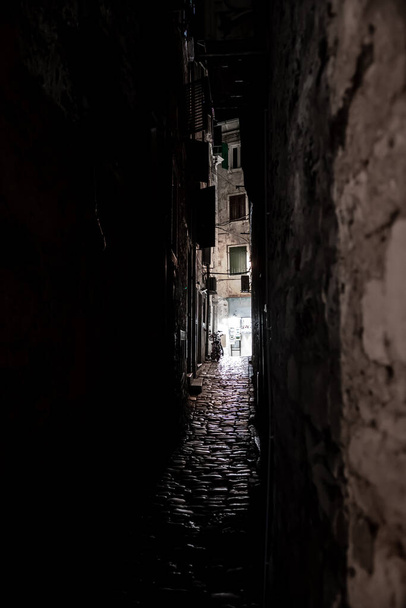 Моторошна вузька алея зі світлом на її кінці, старі будинки і Коблстоун Земля в темну ніч
 - Фото, зображення