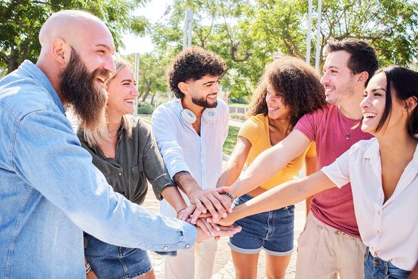 Emberek csoportja, akik jól érzik magukat együtt. Multiracionális mosolygó barátok egymásra rakott kezek egy boldog körben. - Fotó, kép
