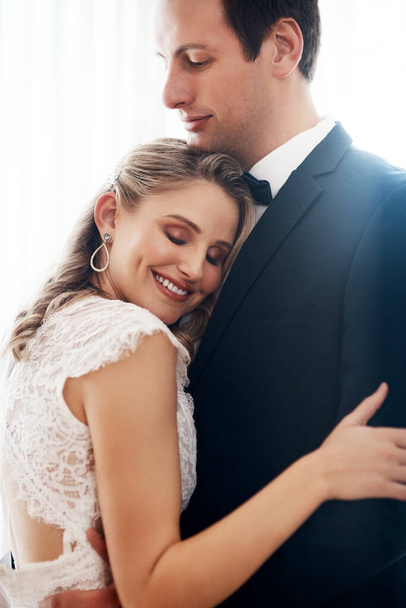 You put your arms around me and I was home. Cropped shot of a happy young couple standing indoors and hugging each other affectionately after their wedding. - Fotoğraf, Görsel