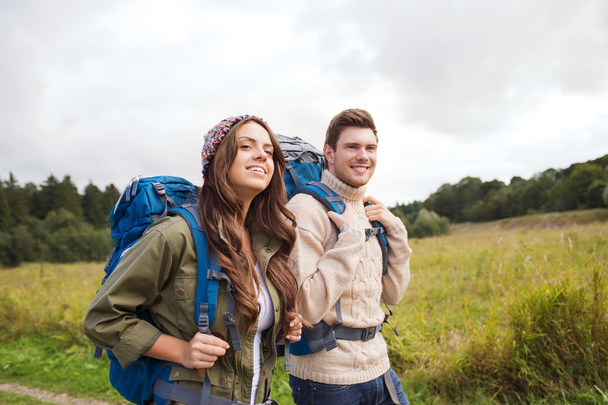 smiling couple with backpacks hiking - Фото, изображение