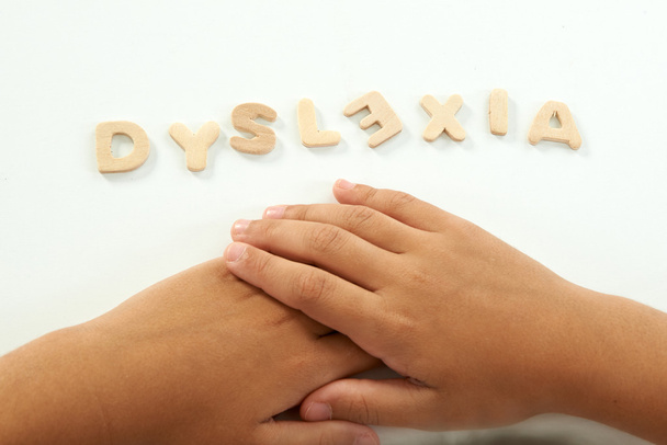 hands of a girl form the word dyslexia with wooden letters - Photo, Image