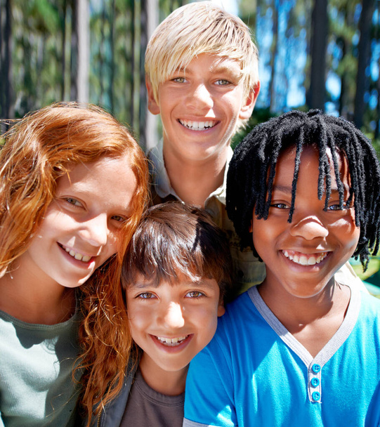 Kampmaatjes. Een divers groepje kinderen glimlachend buiten in het bos. - Foto, afbeelding