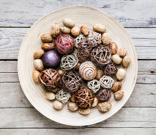 Decorative twig spheres lay in wooden bowl on wooden table - Valokuva, kuva