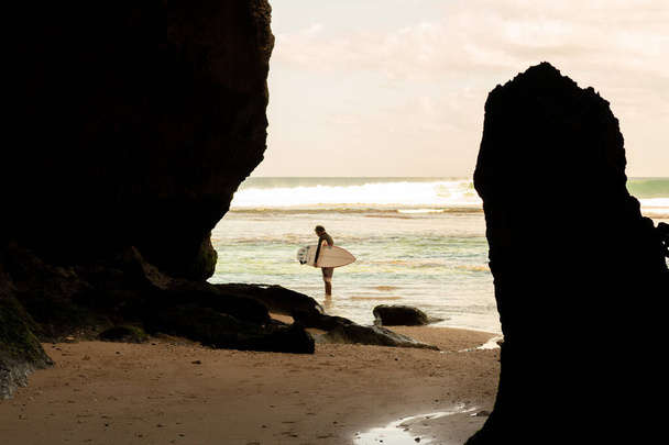 A man walking on the beach with a surfboard. - 写真・画像