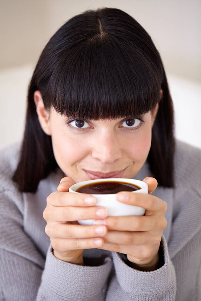 Starting her day with a fresh, strong cup of coffee. Cropped shot of a beautiful young woman enjoying a cup of coffee in the morning. - 写真・画像