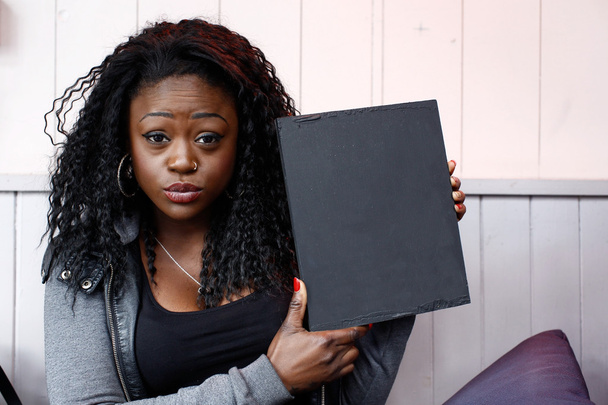 Joven mujer negra sosteniendo pequeña mesa negra
 - Foto, imagen