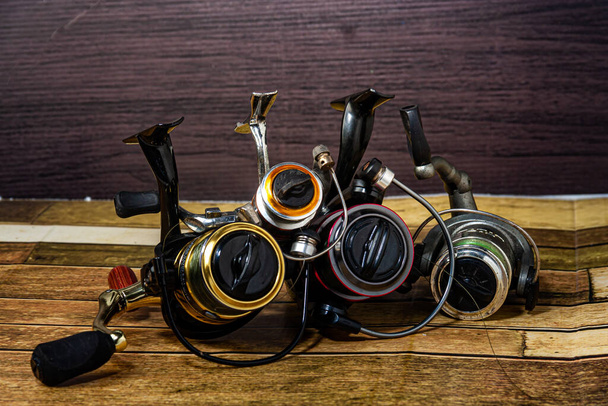 Fishing reel Fishing equipment on wooden wall background, indoors technology system - Photo, Image