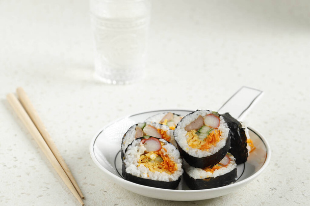 Gimbap de rollo coreano (Kimbob o Kimbap) hecho de arroz blanco al vapor (Bap) y varios otros ingredientes, como Kyuri, zanahoria, salchicha, palo de cangrejo o kimchi y envuelto con algas marinas Laver. Copiar espacio - Foto, Imagen