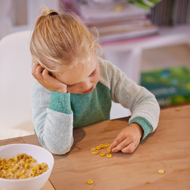 No me gusta este cereal. Foto de una niña pequeña que se ve triste mientras desayuna en casa. - Foto, Imagen