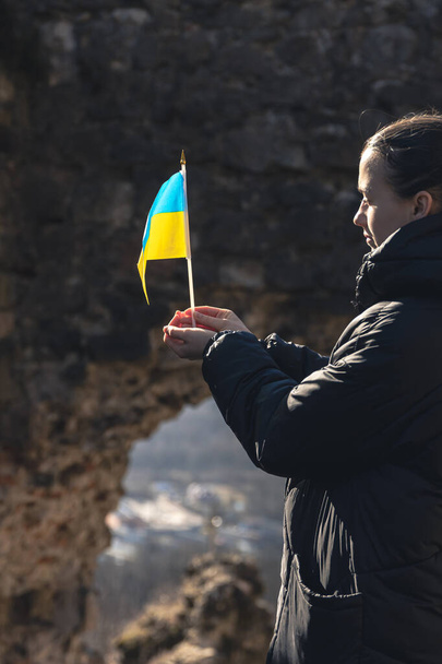 Eine junge Frau mit der Fahne der Ukraine in der Hand. - Foto, Bild