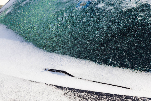 Лёд и снег покрывают лобовое стекло и дворник после снежной бури - Фото, изображение
