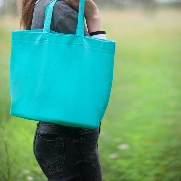 Woman holding emerald green tote bag, no face, outdoor - Foto, Imagen