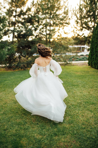 Beautiful wedding bride running in the garden - Photo, Image