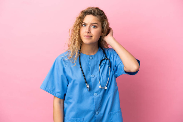 Jeune chirurgien médecin femme isolée sur fond rose ayant des doutes - Photo, image