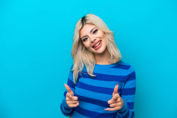 Young Russian woman isolated on blue background surprised and pointing front - Fotó, kép