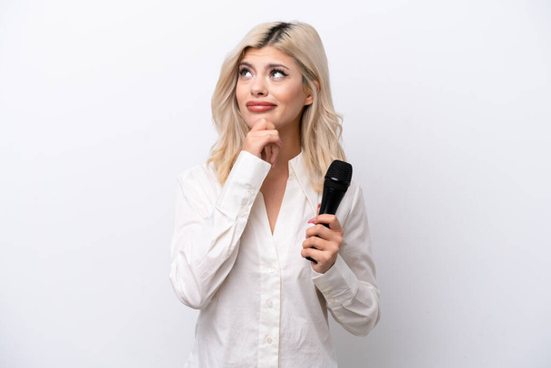 Giovane cantante donna raccogliendo un microfono isolato su sfondo bianco e guardando in alto - Foto, immagini