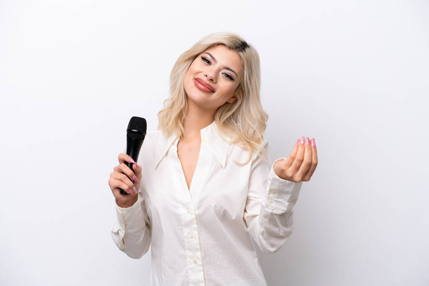 Nuori laulaja nainen poimien mikrofoni eristetty valkoisella taustalla tehdä rahaa ele - Valokuva, kuva