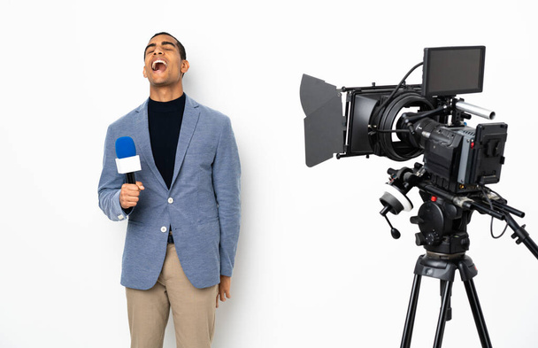 Reportér Afroameričan drží mikrofon a reportáž zprávy přes izolované bílé pozadí se směje - Fotografie, Obrázek