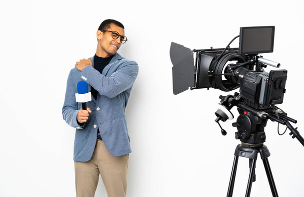 Δημοσιογράφος Αφροαμερικανός που κρατάει μικρόφωνο και μεταδίδει ειδήσεις σε απομονωμένο λευκό φόντο που υποφέρει από πόνο στον ώμο επειδή έκανε μια προσπάθεια - Φωτογραφία, εικόνα