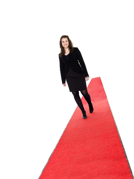 lachende meisje lopen op rood tapijt - Foto, afbeelding
