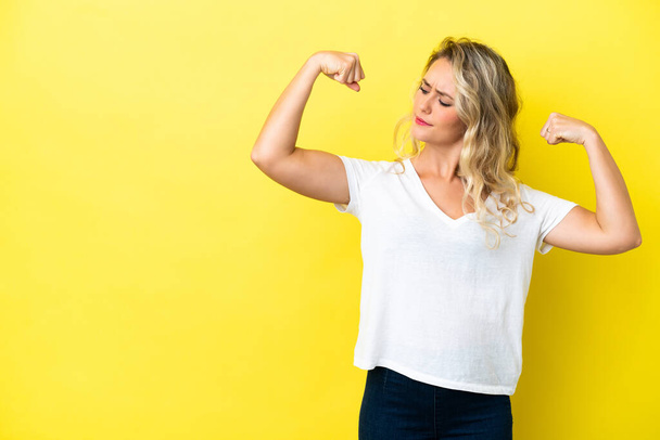 Young Brazilian woman isolated on yellow background doing strong gesture - Foto, Bild
