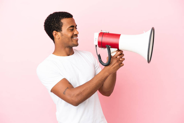 African American handsome man on isolated pink background shouting through a megaphone to announce something - Photo, Image