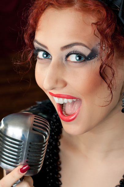 Redhead woman singing into vintage microphone - Foto, imagen